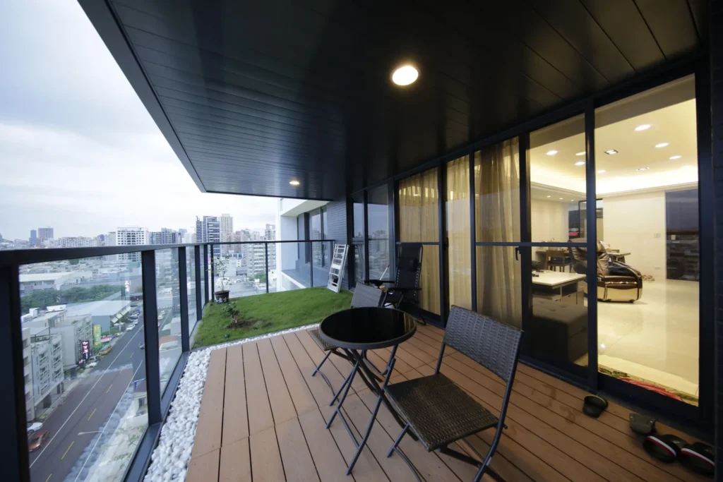 重立路陽台設計，塑木地板搭配白色鵝卵石造景與高樓景觀